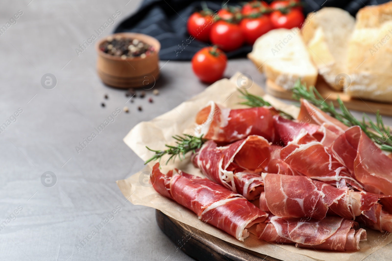 Photo of Slices of tasty prosciutto on grey table