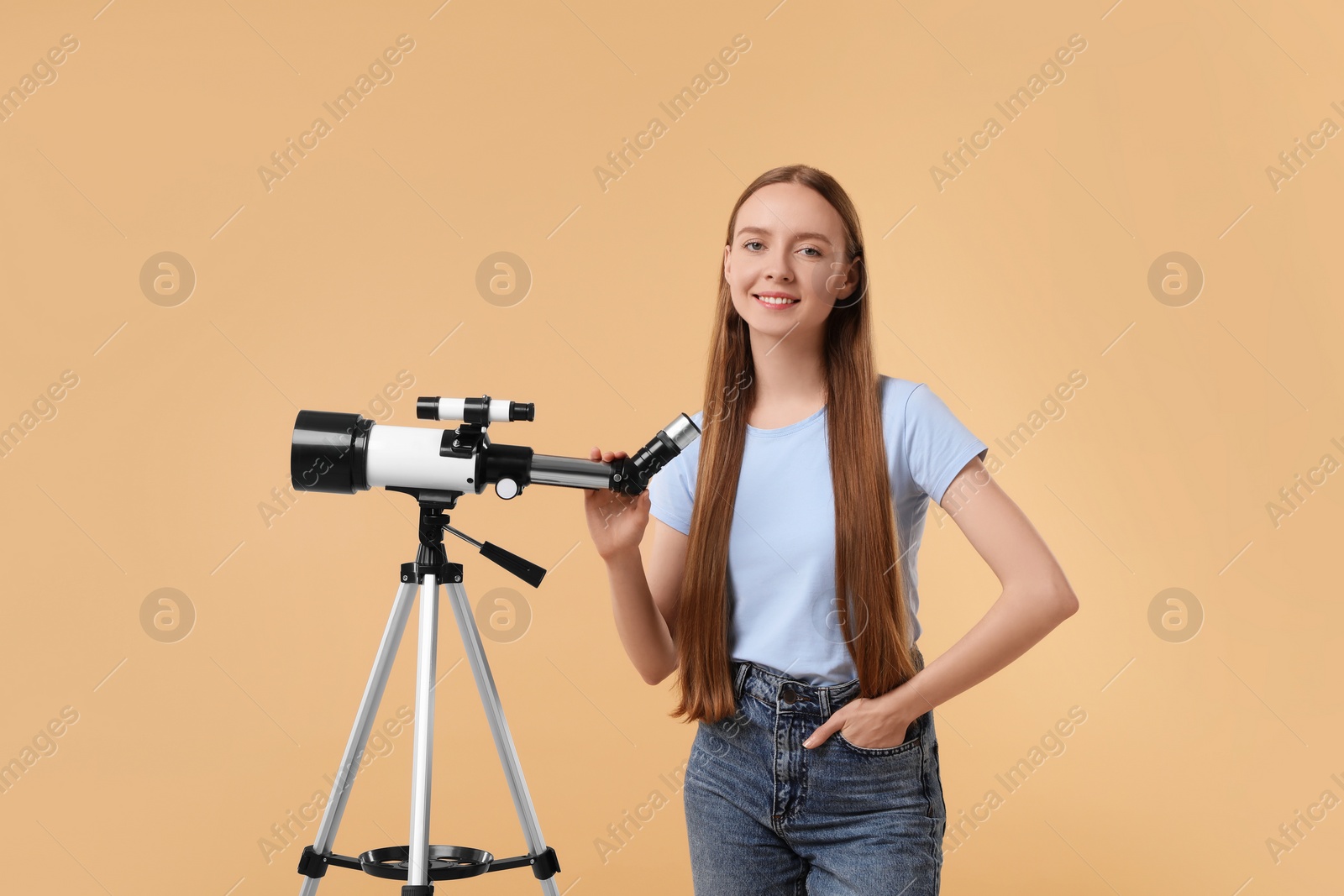 Photo of Happy astronomer with telescope on beige background