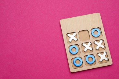 Tic tac toe set on bright pink background, top view. Space for text