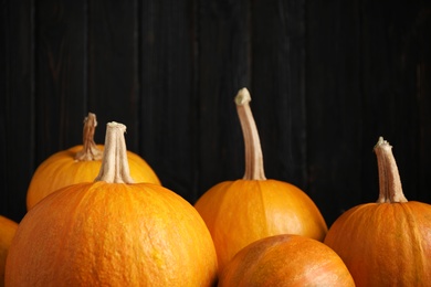 Photo of Orange pumpkins on black background, closeup. Holiday decoration