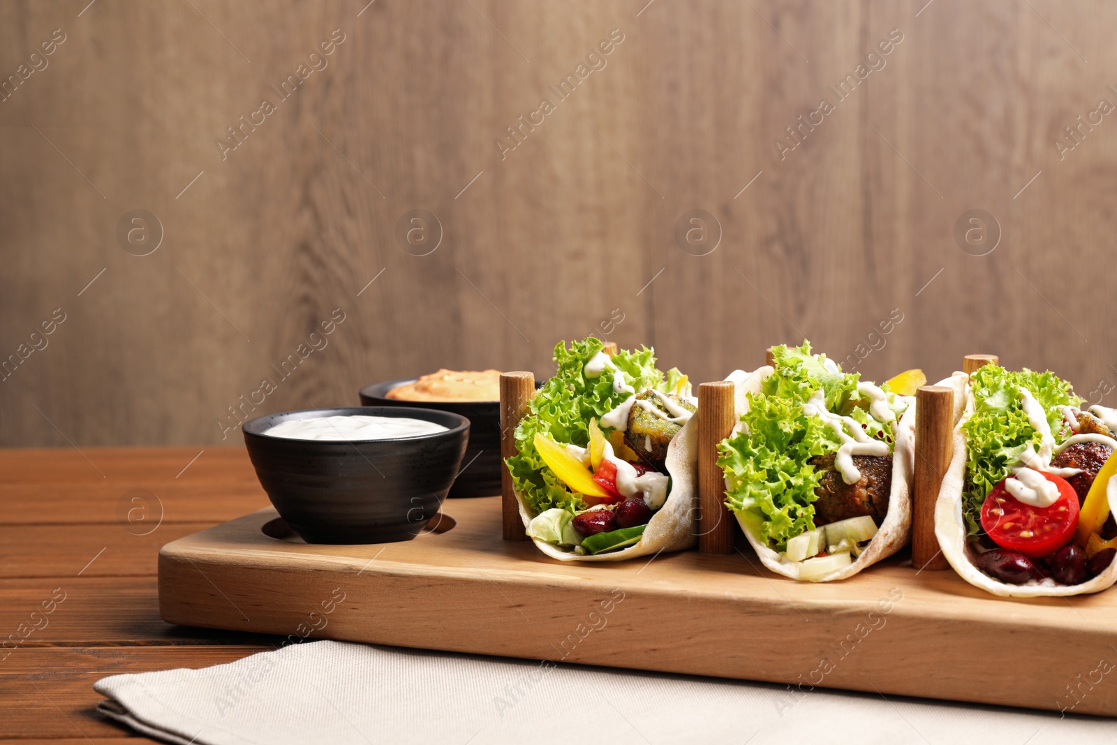 Photo of Delicious fresh vegan tacos served on wooden table. Space for text