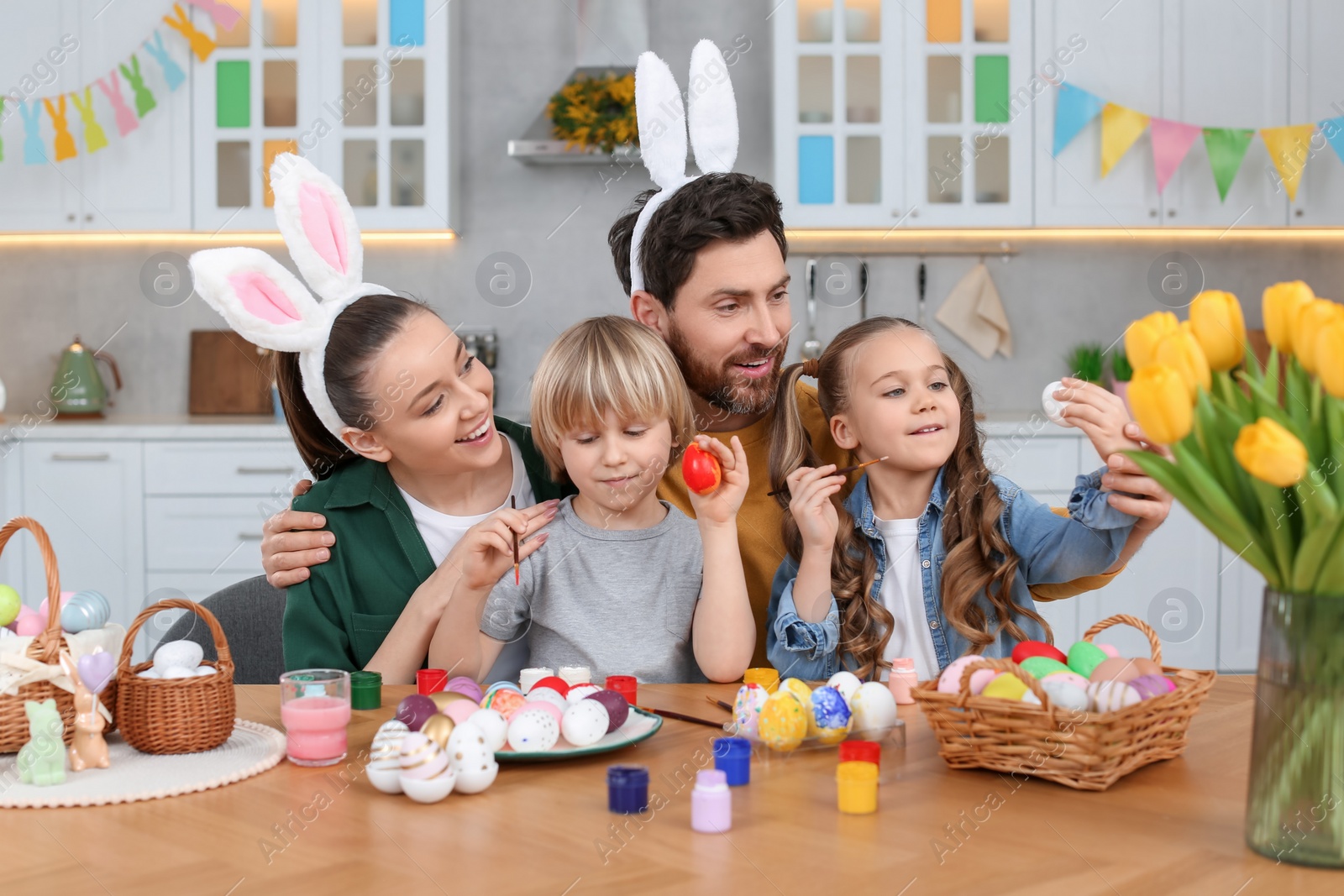 Photo of Happy family painting Easter eggs at table in kitchen