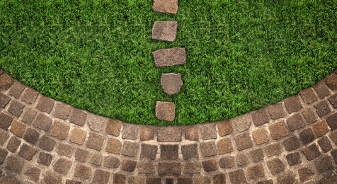 Fresh green grass and stone tiles outdoors, top view. Banner design