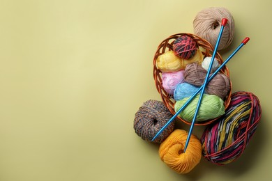 Photo of Soft woolen yarns and knitting needles on yellow background, flat lay. Space for text