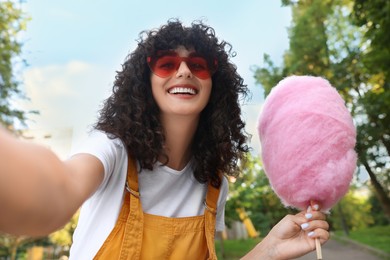 Happy woman with cotton candy taking selfie at funfair