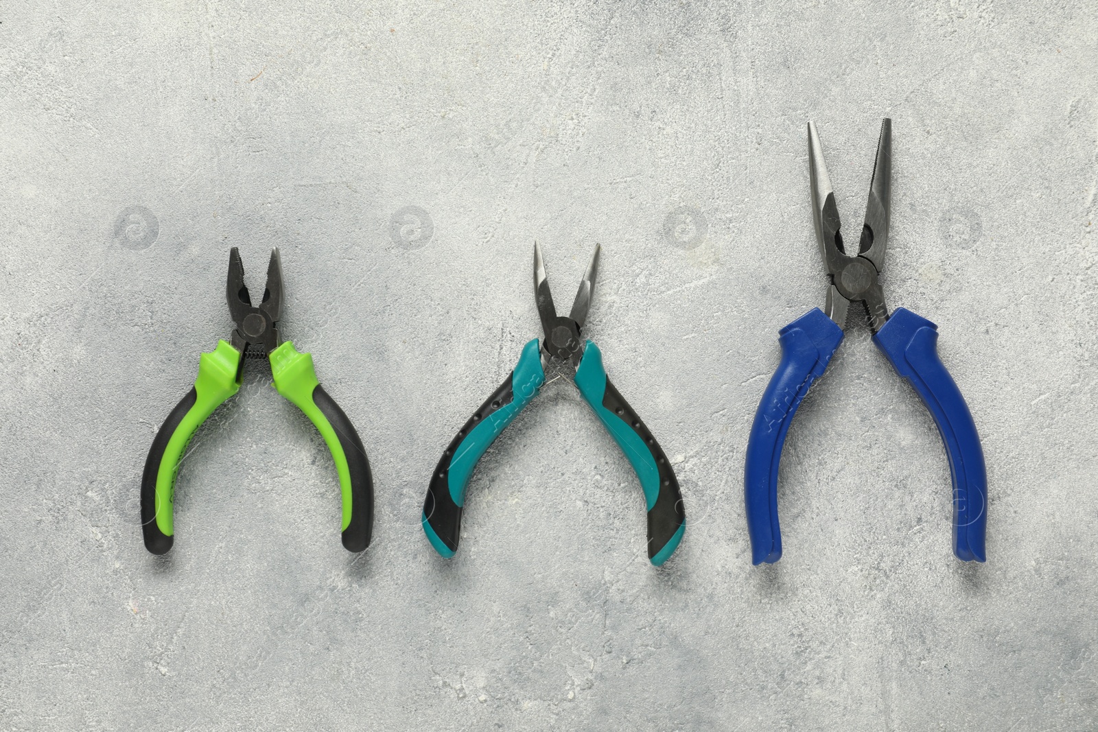 Photo of Different pliers on grey textured table, flat lay