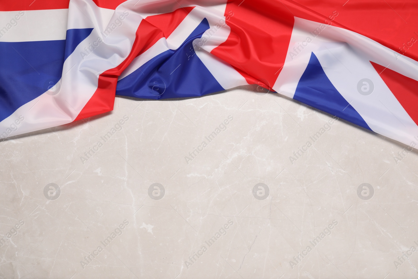 Photo of Flag of United Kingdom on beige marble background, top view. Space for text