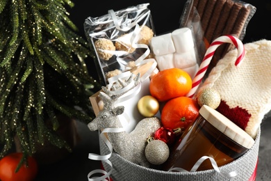 Photo of Basket with Christmas gift set and small fir tree on table