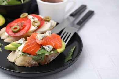 Photo of Different tasty bruschettas served on white tiled table, closeup