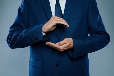 Photo of Businessman holding something on grey background, closeup of hands