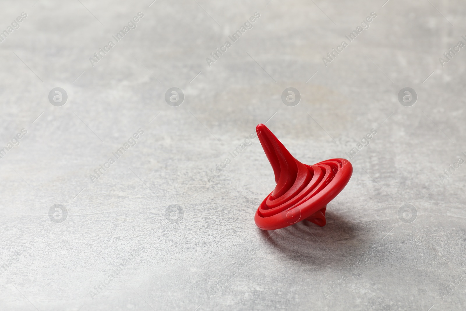 Photo of Red spinning top on grey textured background, closeup. Space for text