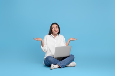 Photo of Puzzled young woman with laptop on light blue background