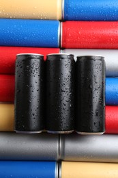 Energy drinks in wet cans as background, top view