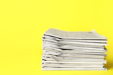 Photo of Stack of newspapers on yellow background. Journalist's work