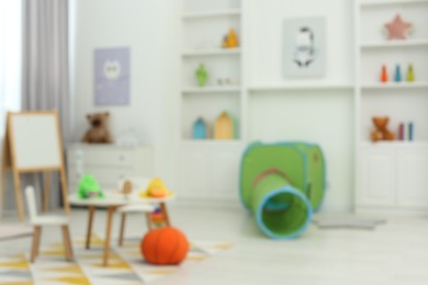 Photo of Blurred view of child`s playroom with different toys and furniture. Stylish kindergarten interior