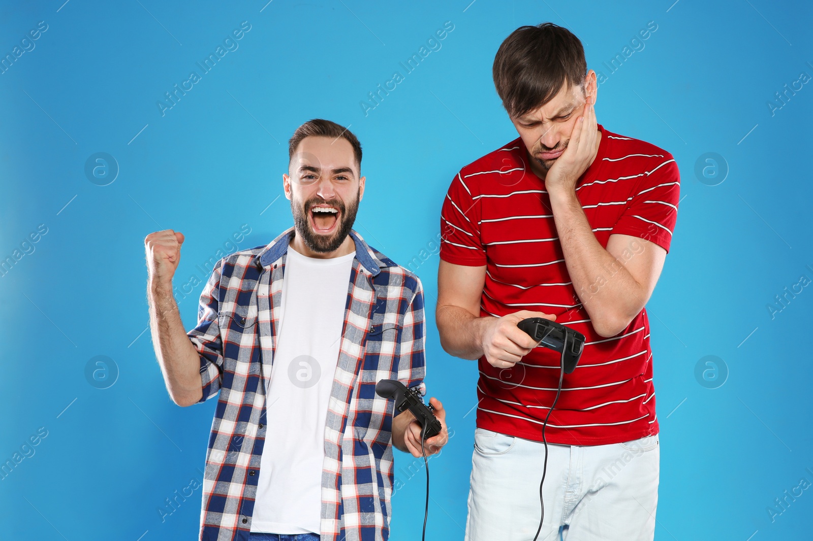 Photo of Emotional men playing video games with controllers on color background