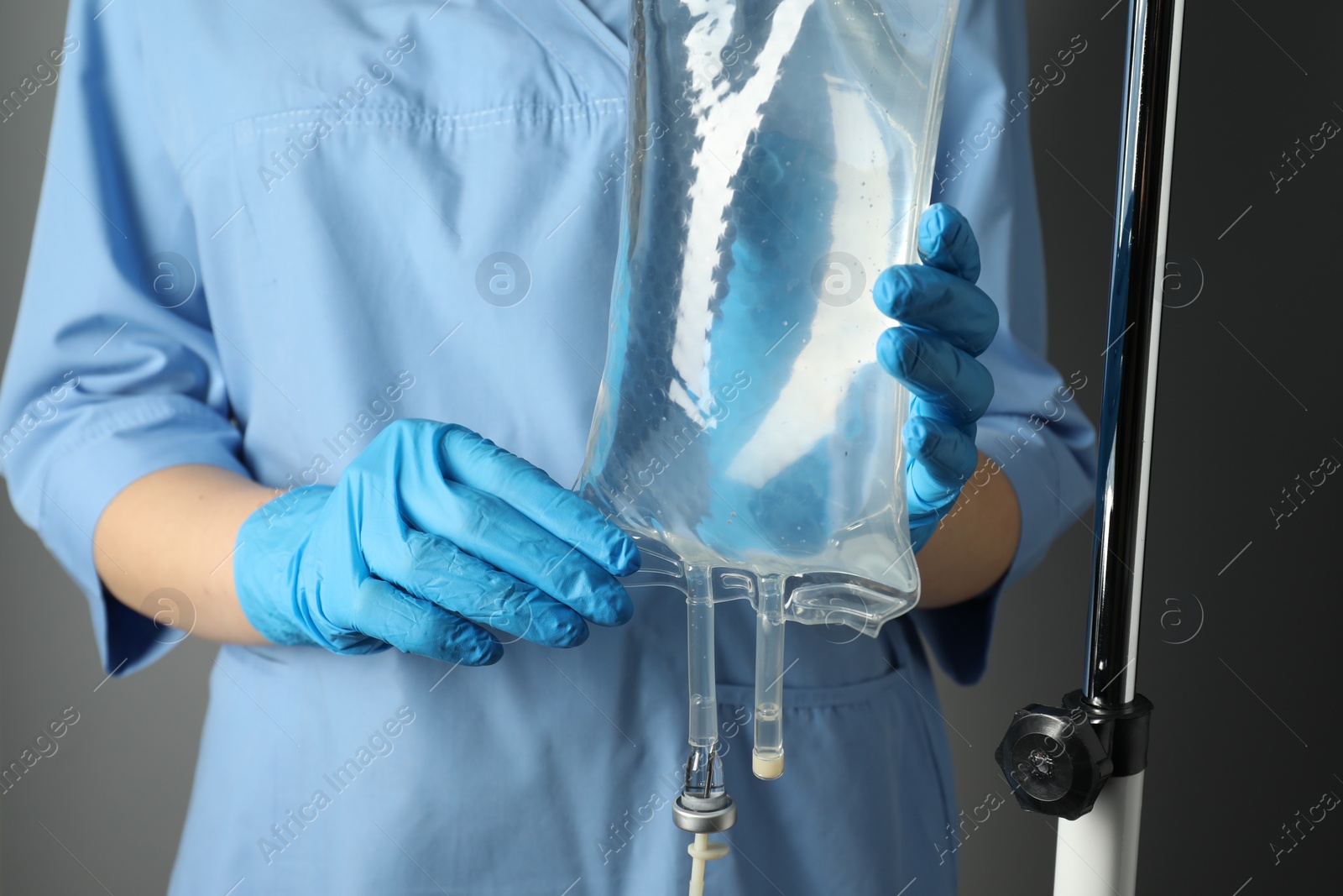 Photo of Nurse with IV infusion set on grey background, closeup