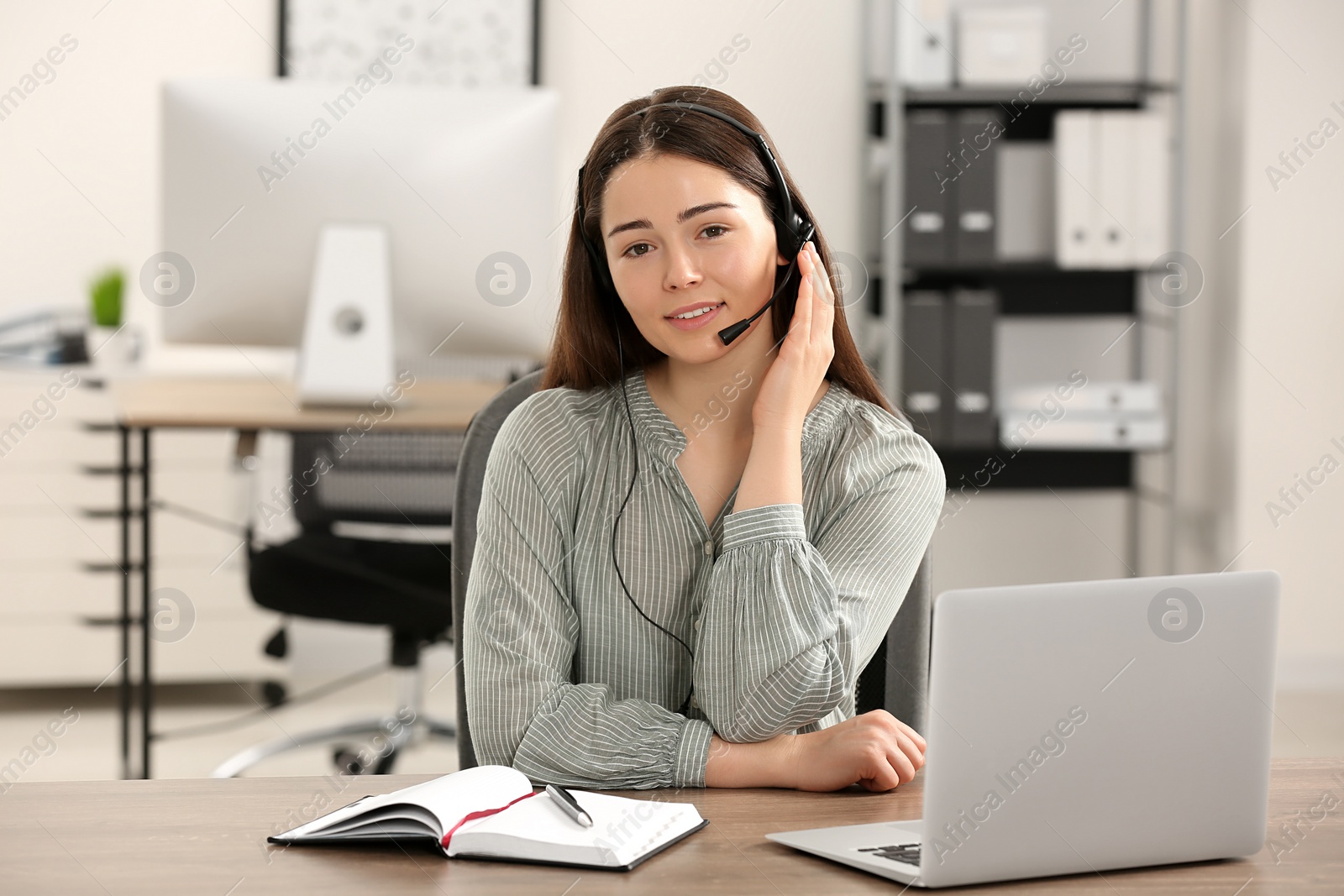 Photo of Hotline operator with headset working on laptop in office