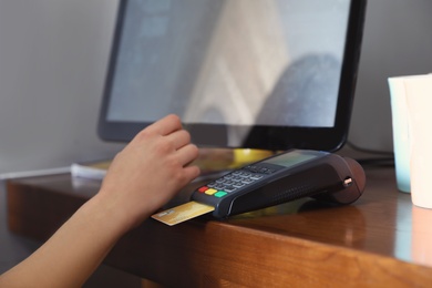 Woman using credit card machine for non cash payment in cafe, closeup