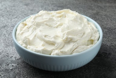 Photo of Bowl of tasty cream cheese on grey table