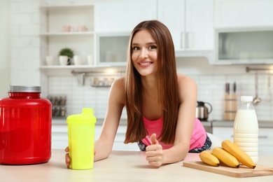 Photo of Young woman with bottle of protein shake in kitchen