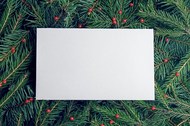 Photo of Blank card on Christmas tree branches as background, top view. Space for text