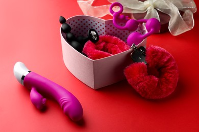 Photo of Gift box with different sex toys on red background