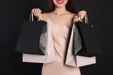 Photo of Woman with shopping bags on black background, closeup. Big sale