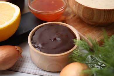 Fresh marinades in bowls and ingredients on white wooden table, closeup