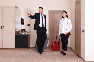 Photo of Happy businesspeople with suitcases walking into hotel room
