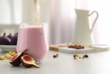 Photo of Delicious fig smoothie in glass on light table. Space for text