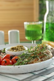 Photo of Tasty chicken, vegetables with tarragon and pesto sauce served on table, closeup