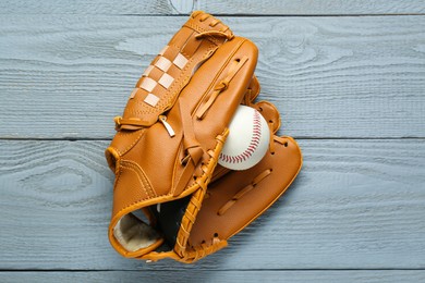 Photo of Leather baseball glove with ball on grey wooden table, top view