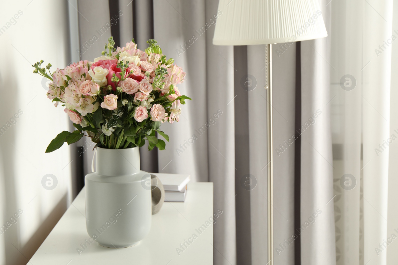 Photo of Beautiful bouquet of fresh flowers in vase on white table indoors, space for text