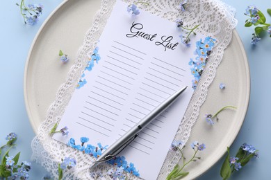 Photo of Plate with guest list, pen, lace and flowers on light blue background, flat lay. Space for text
