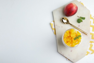 Tasty peach dessert with yogurt served on white table, top view. Space for text