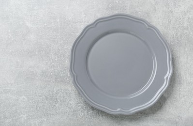 Empty ceramic plate on light grey table, top view. Space for text