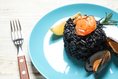 Delicious black risotto with seafood on white wooden table, closeup
