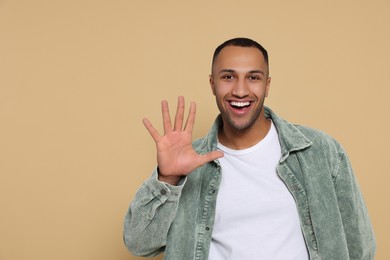 Man giving high five on beige background. Space for text