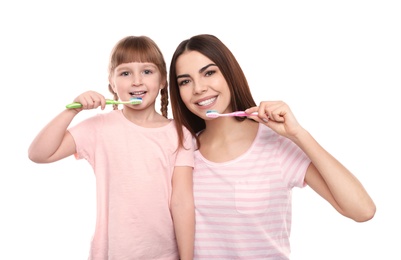 Photo of Little girl and her mother brushing teeth together on white background