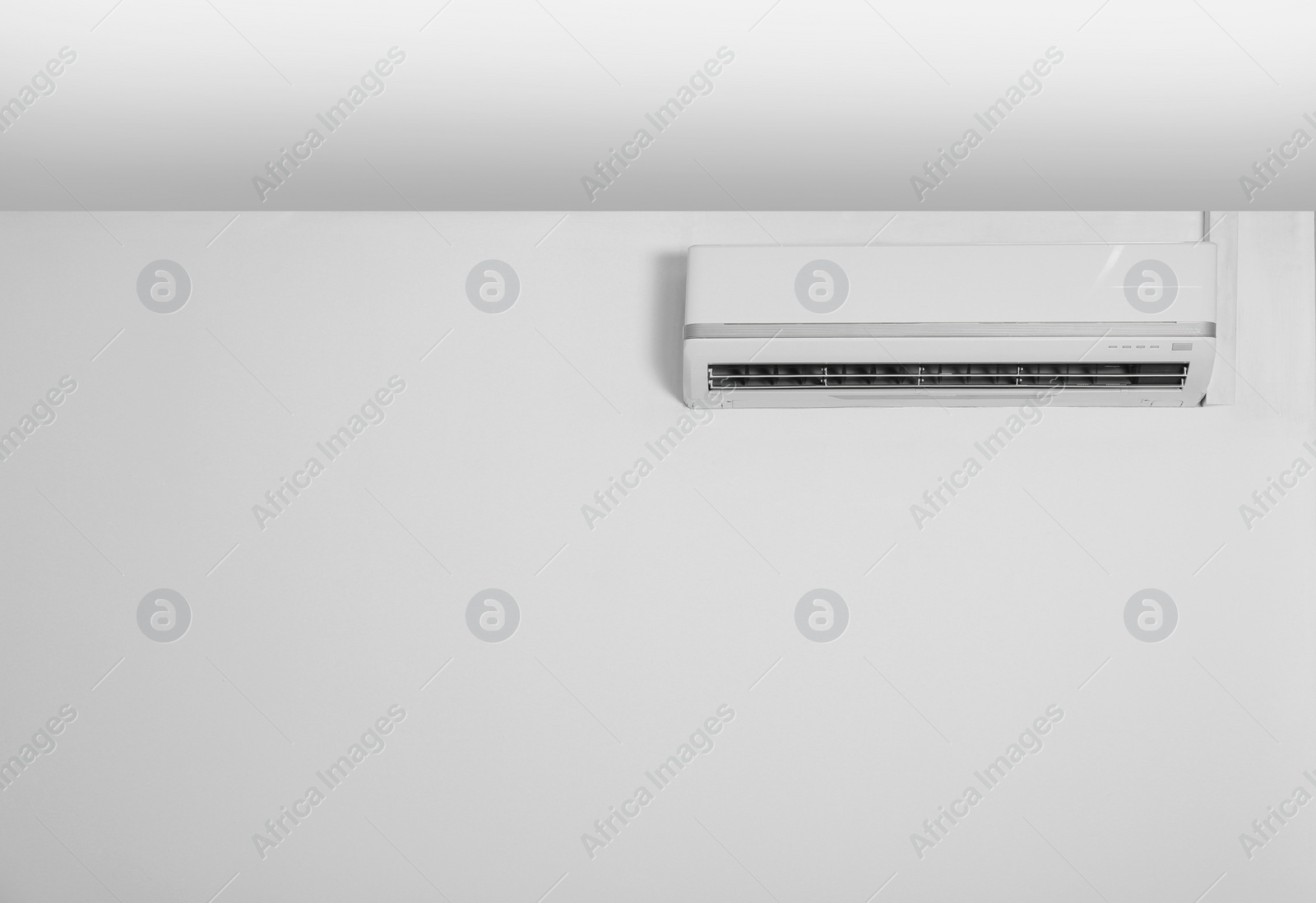 Photo of Modern air conditioner on white wall indoors