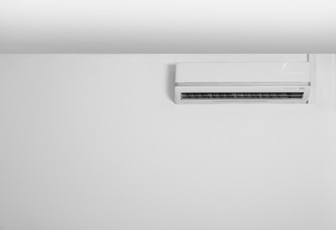 Modern air conditioner on white wall indoors