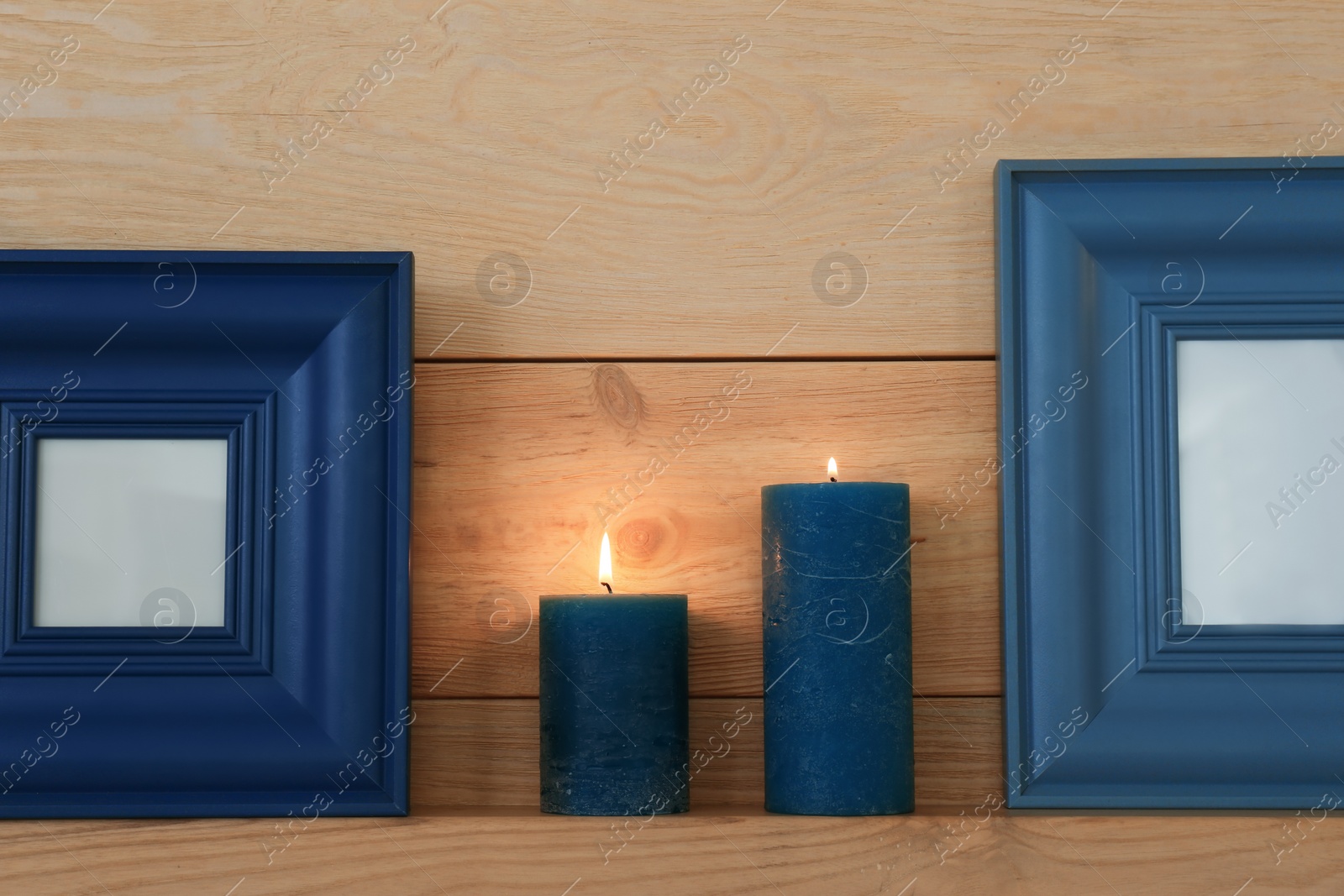 Photo of Shelf with burning candles against wooden wall