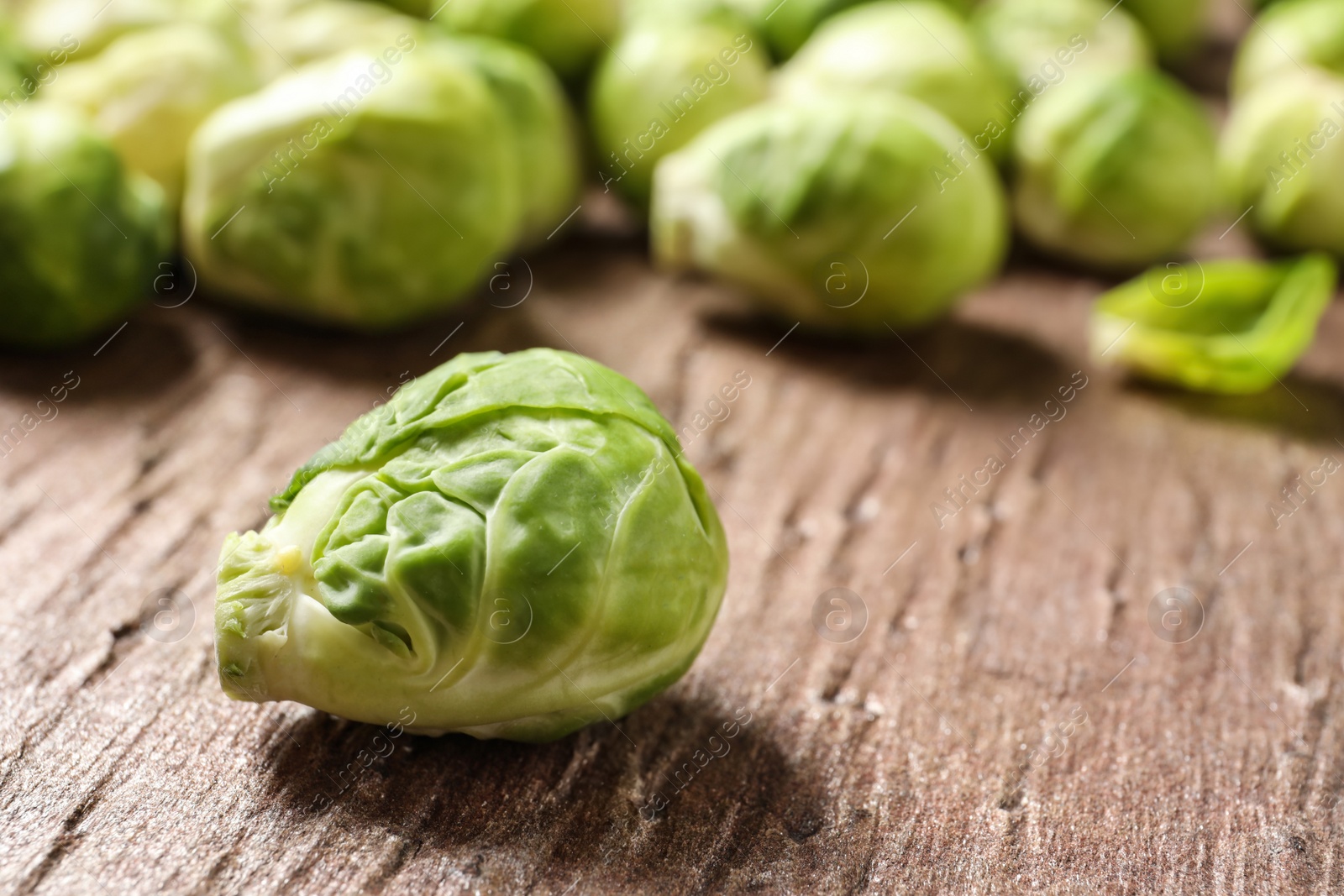 Photo of Fresh Brussels sprouts on wooden table, closeup. Space for text