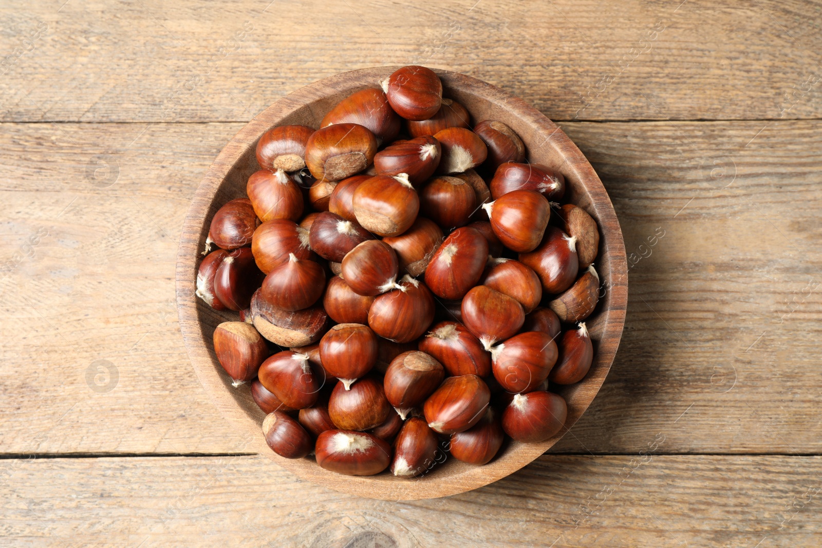 Photo of Fresh sweet edible chestnuts on wooden table, top view