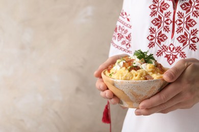 Photo of Woman holding bowl of delicious traditional Ukrainian banosh on beige background, closeup. Space for text