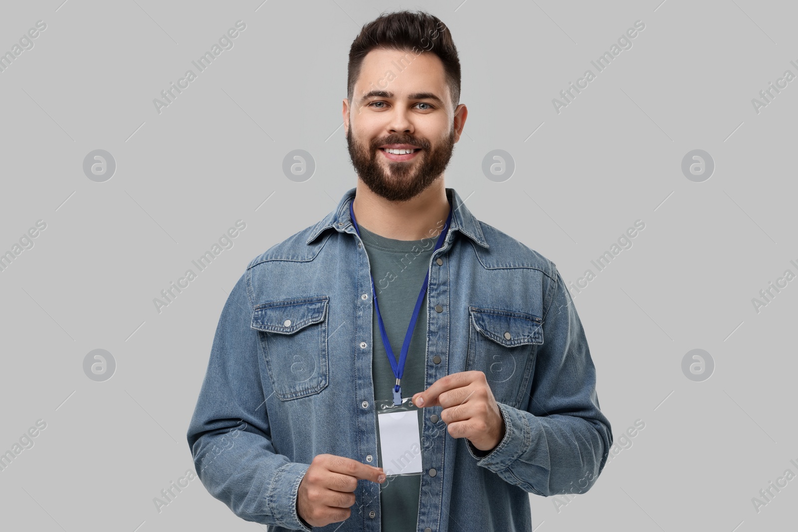 Photo of Happy young man with blank badge on grey background