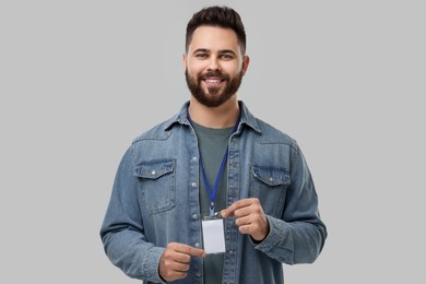 Photo of Happy young man with blank badge on grey background