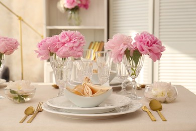 Photo of Stylish table setting with beautiful peonies and fabric napkin indoors