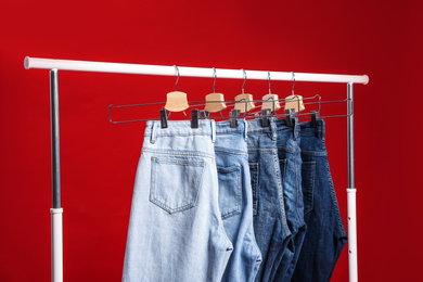 Photo of Rack with different jeans on red background